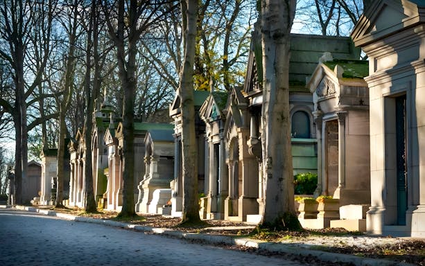 Tombs and trees lining a path inside Père Lachaise Cemetery, Paris.