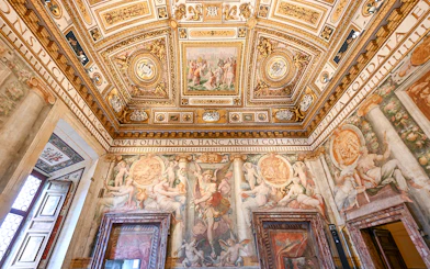 Interior of Castel Sant'Angelo with ornate ceiling and detailed frescoes in Rome, Italy.