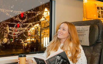 Guests enjoying scenic view from Flåm Railway in Bergen, Norway, with festive lights outside.