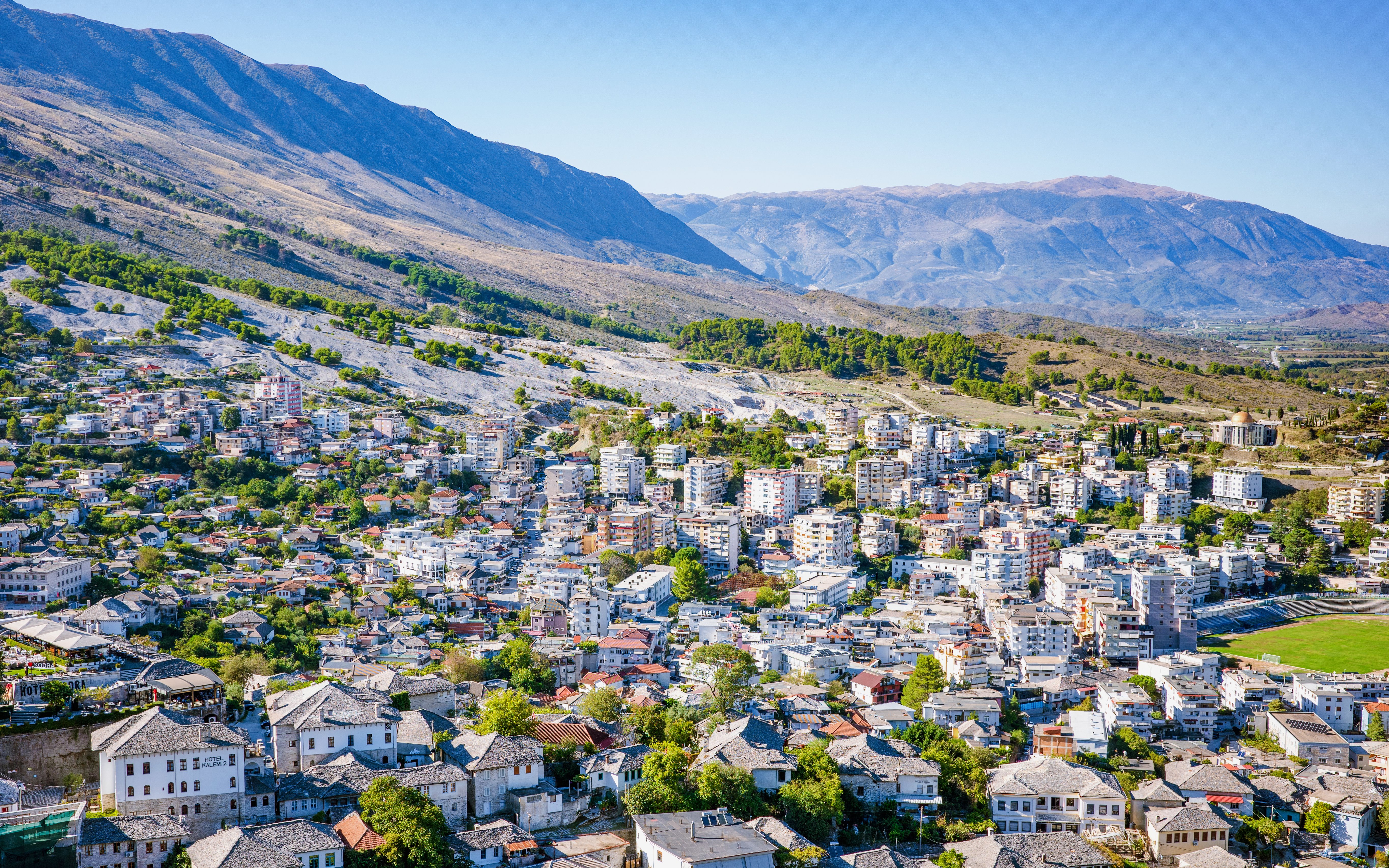 Panoramic view of Gjirokastra town with traditional stone houses and surrounding mountains.