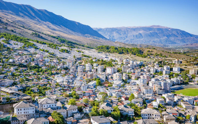 Panoramic view of Gjirokastra town with traditional stone houses and surrounding mountains.