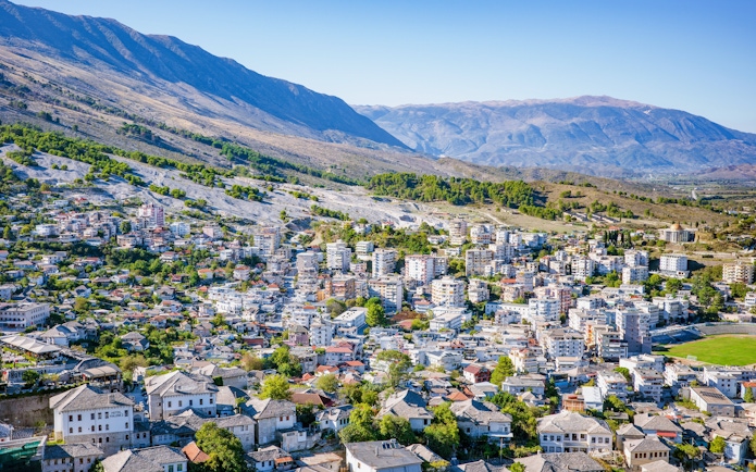 Panoramic view of Gjirokastra town with traditional stone houses and surrounding mountains.