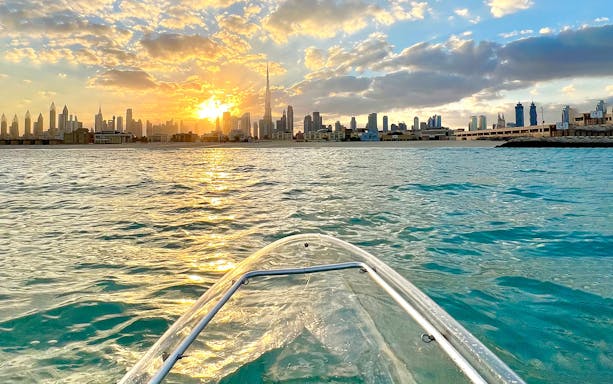 Clear kayak on water with Burj Khalifa and Dubai skyline at sunset.