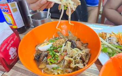 Chiang Mai street food bowl with noodles, mushrooms, and herbs on a Michelin food tour.