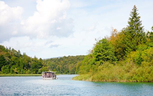 Boat on Plitvice Lakes surrounded by lush greenery, Croatia.