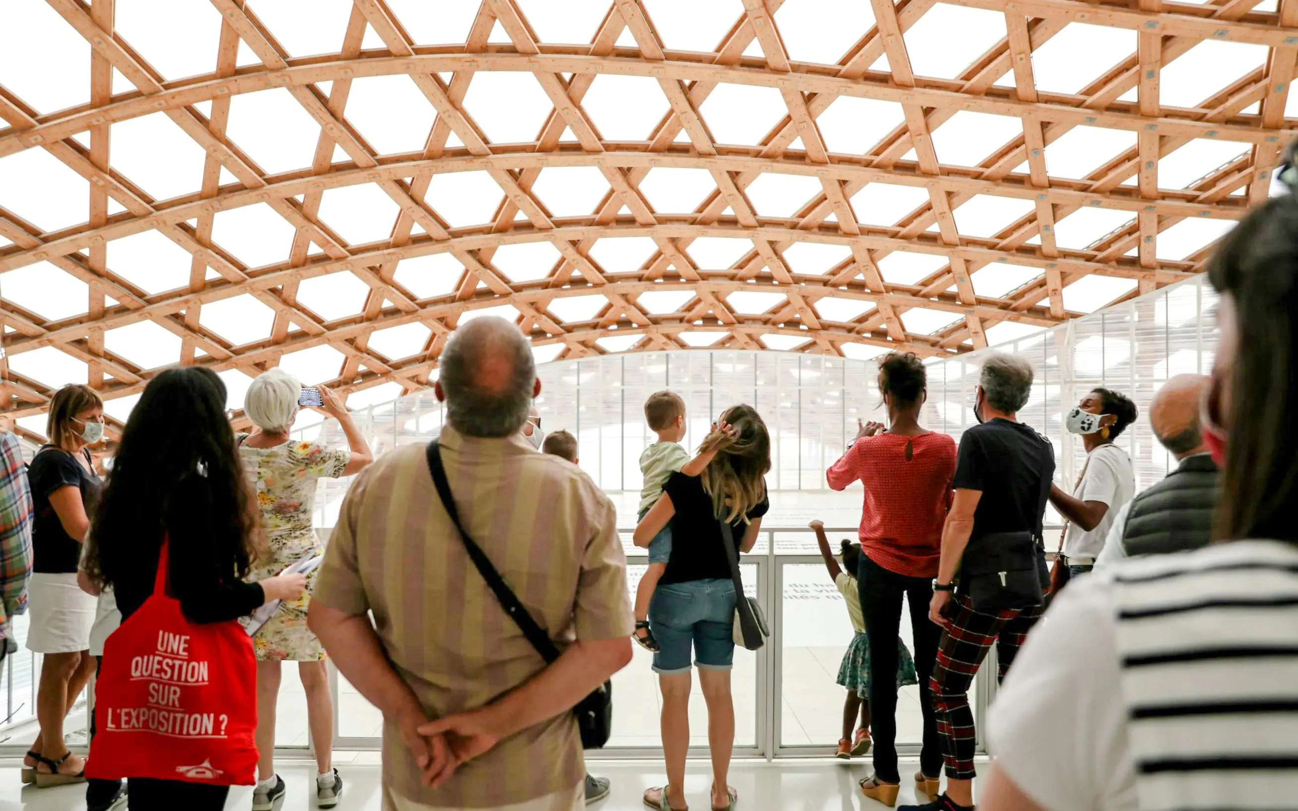 Visitors observing the wooden lattice roof at Centre Pompidou-Metz, France.