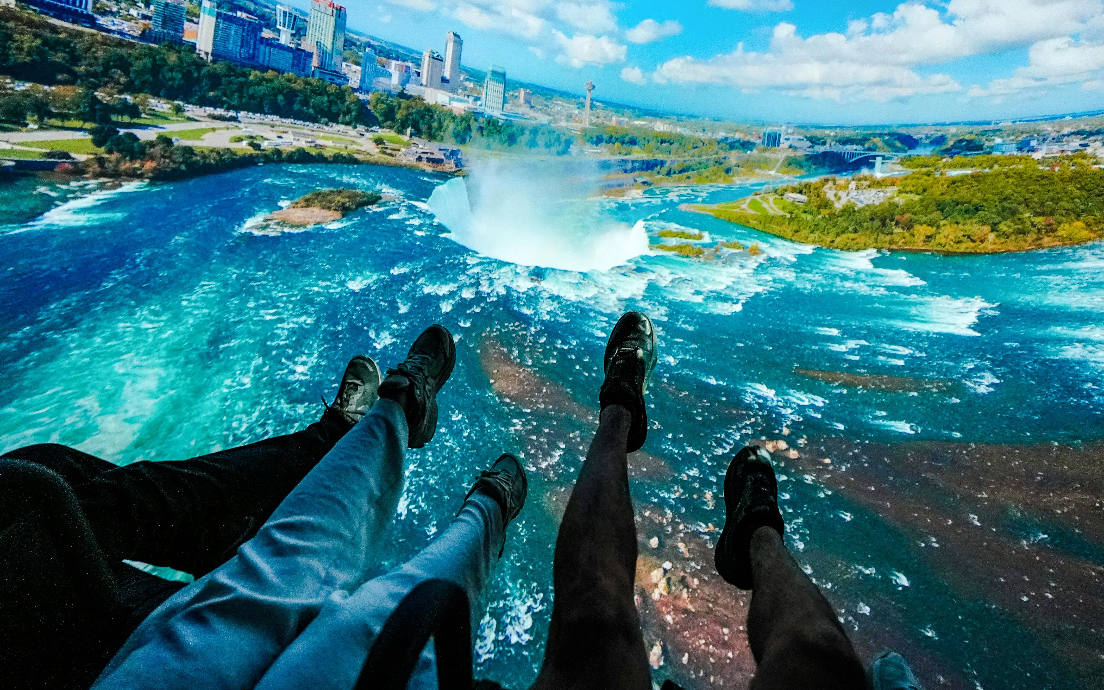 Aerial view of Niagara Falls with tourists' feet visible, Canada.