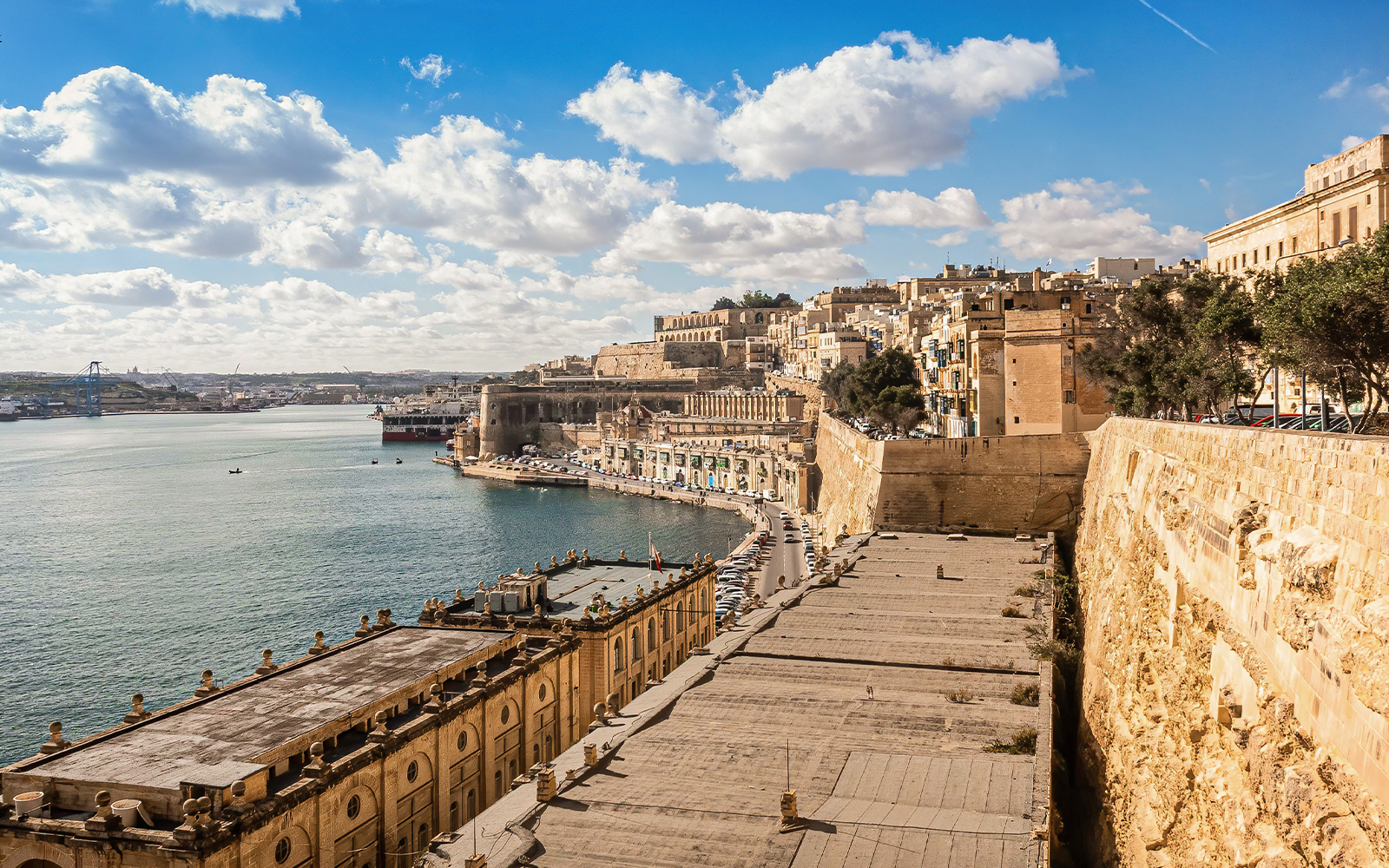 Valletta waterfront with historic buildings and harbor on a sunny day, Malta.