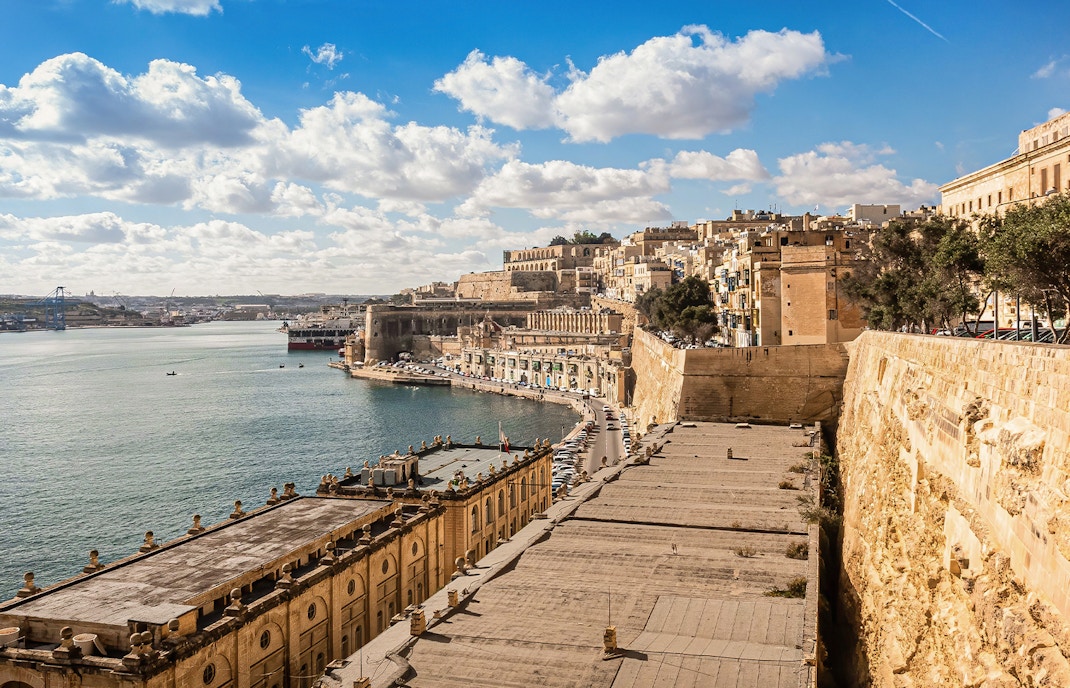 Valletta waterfront with historic buildings and harbor on a sunny day, Malta.