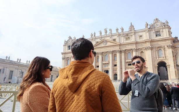St. Peter’s Basilica interior with visitors on a guided tour in Vatican City.
