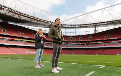 Visitors standing on the field of Emirates Stadium, London.