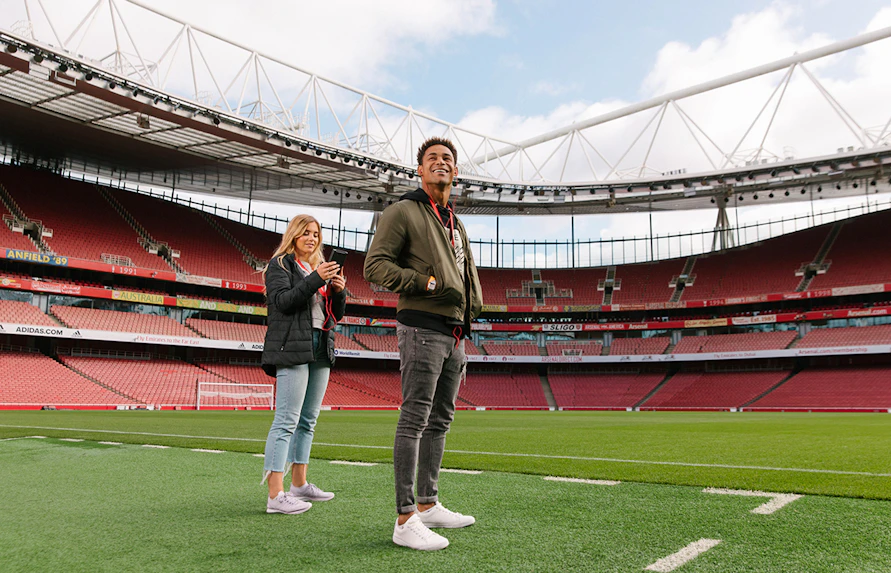 Visitors standing on the field of Emirates Stadium, London.