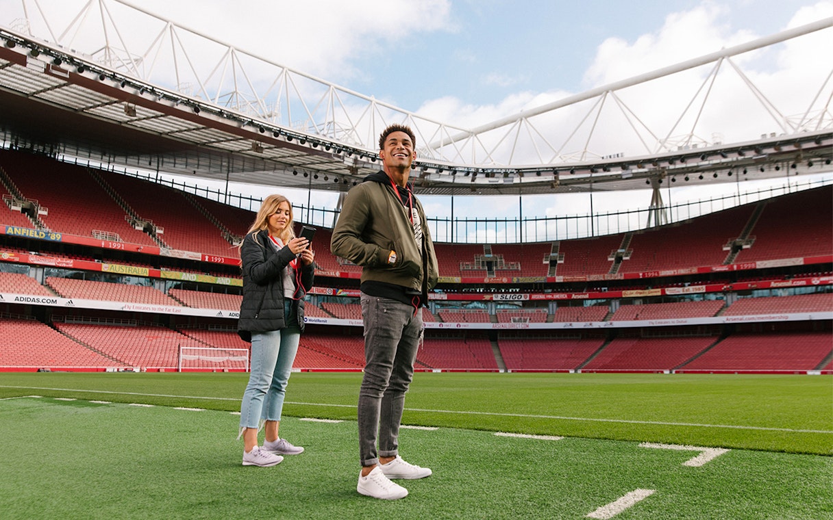 Visitors standing on the field of Emirates Stadium, London.