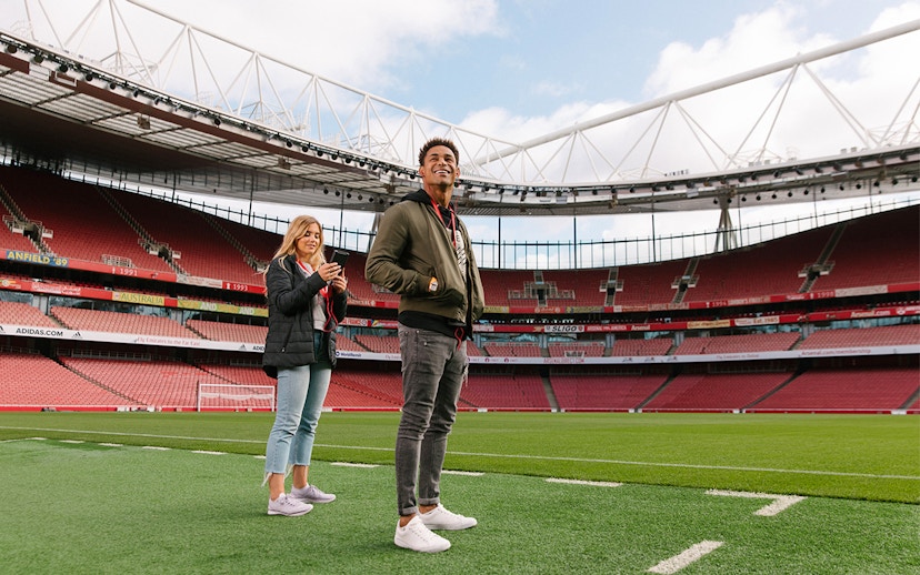 Visitors standing on the field of Emirates Stadium, London.