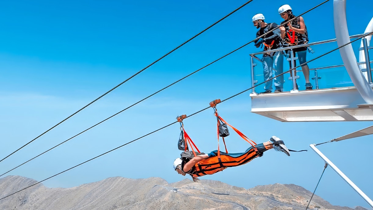 Person ziplining over Jebel Jais mountains, observed by onlookers, Jais Flight, Dubai.