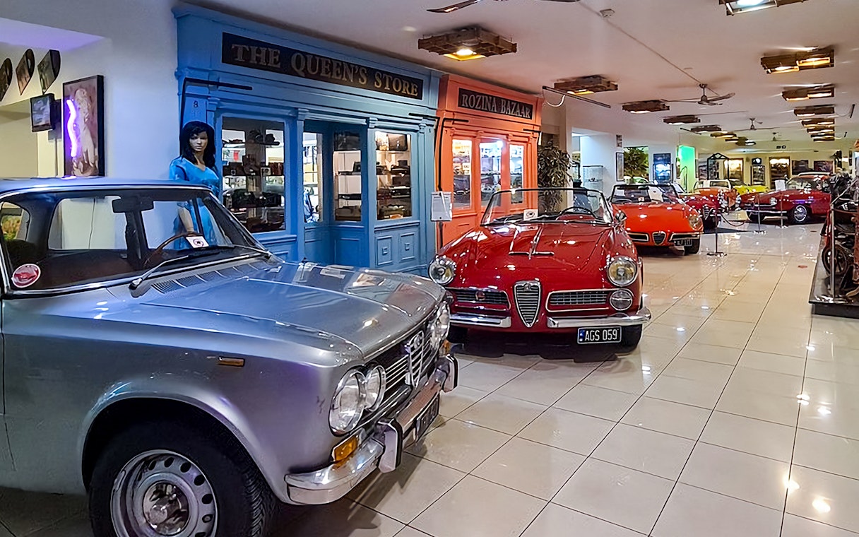 Classic cars and motorcycles displayed in a vintage-themed showroom.