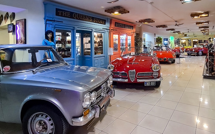 Classic cars and motorcycles displayed in a vintage-themed showroom.