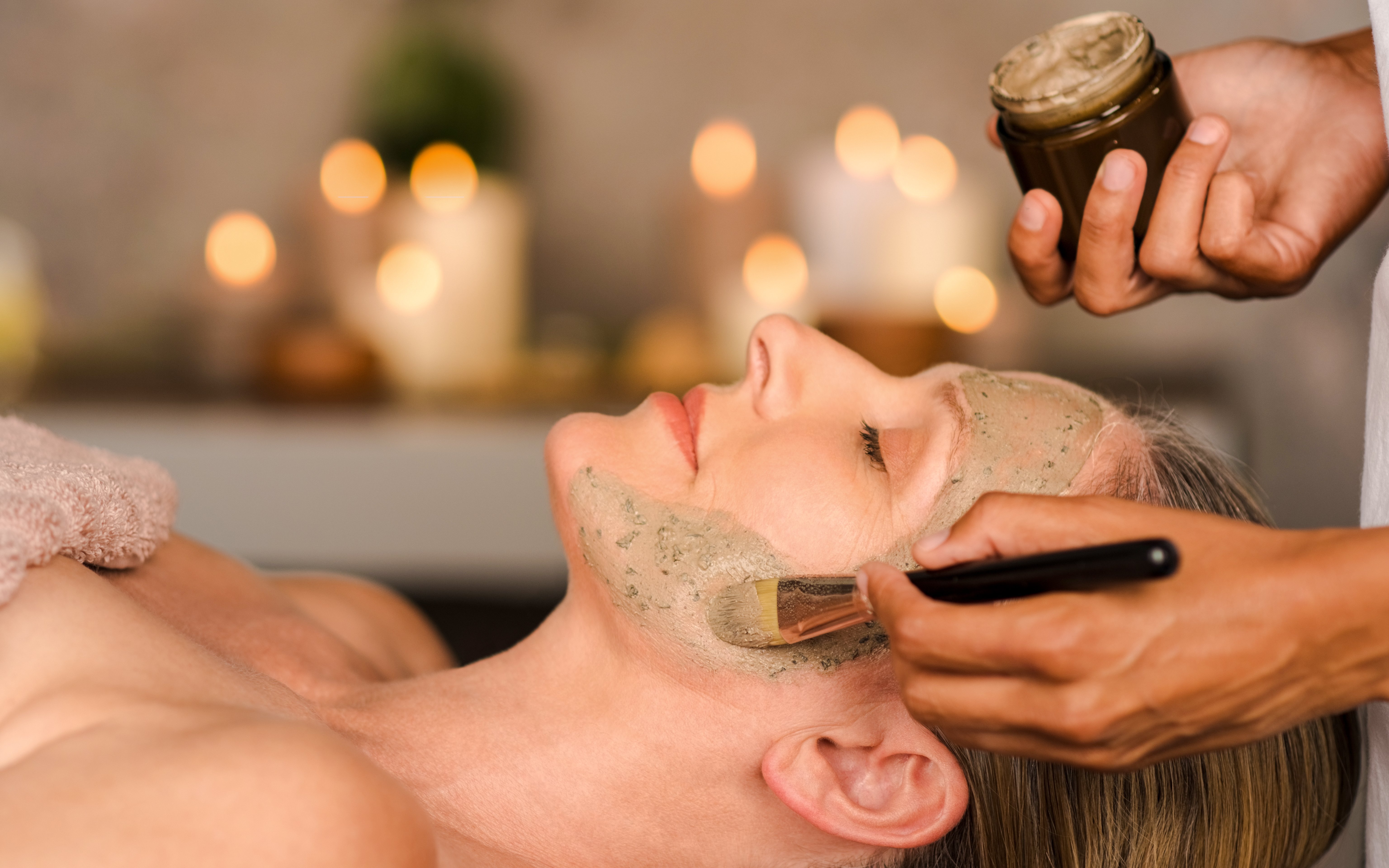 Woman receiving a facial mask application in a spa setting.