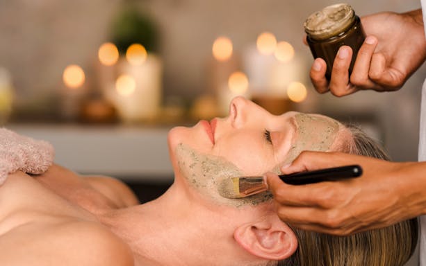 Woman receiving a facial mask application in a spa setting.