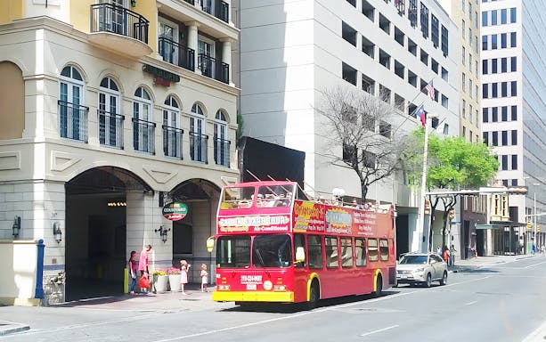Red double-decker bus on San Antonio street for Hop-On Hop-Off tour near Courtyard Marriott.
