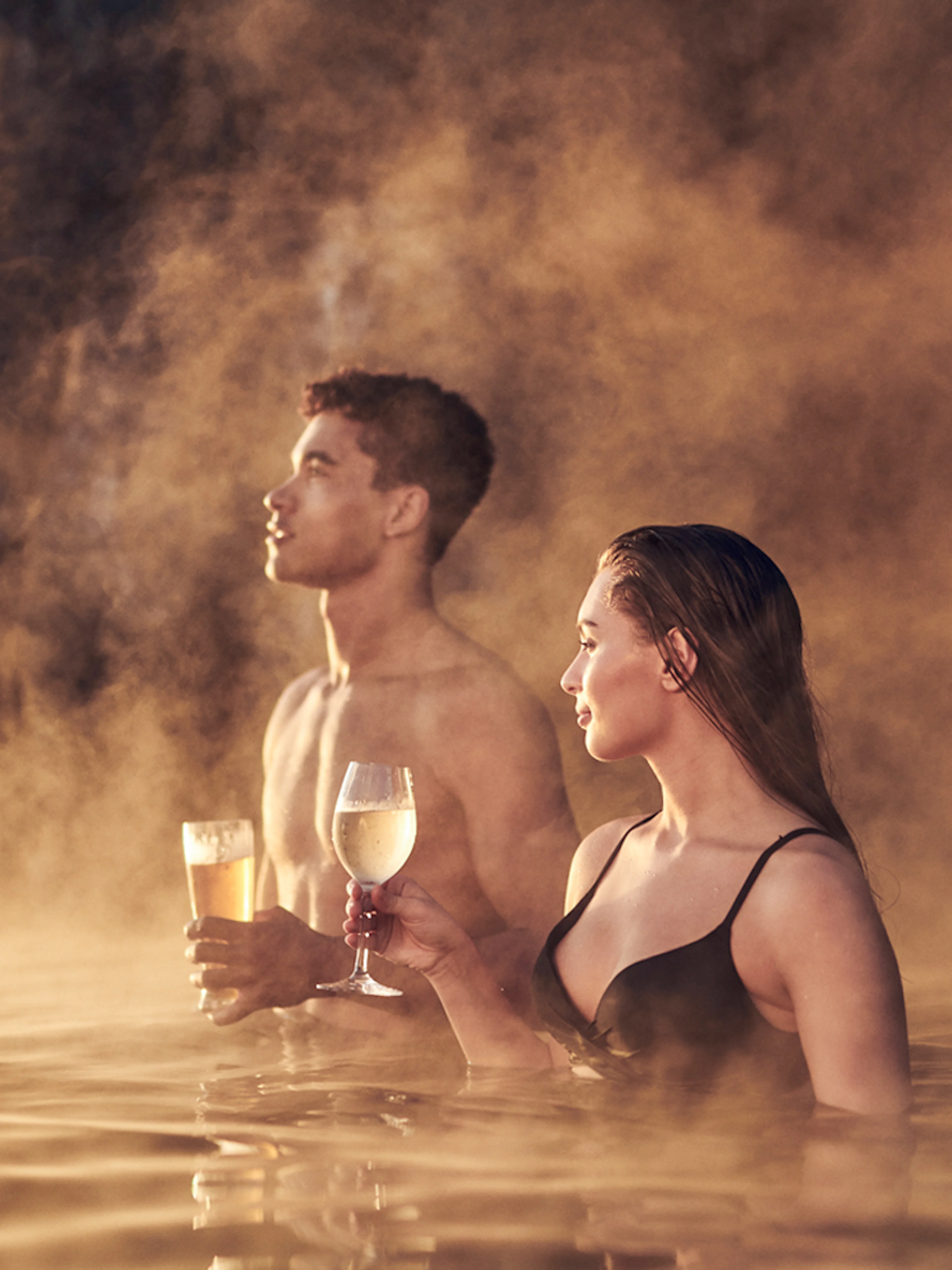 Couple enjoying drinks in the warm waters of Sky Lagoon Saman Pass.