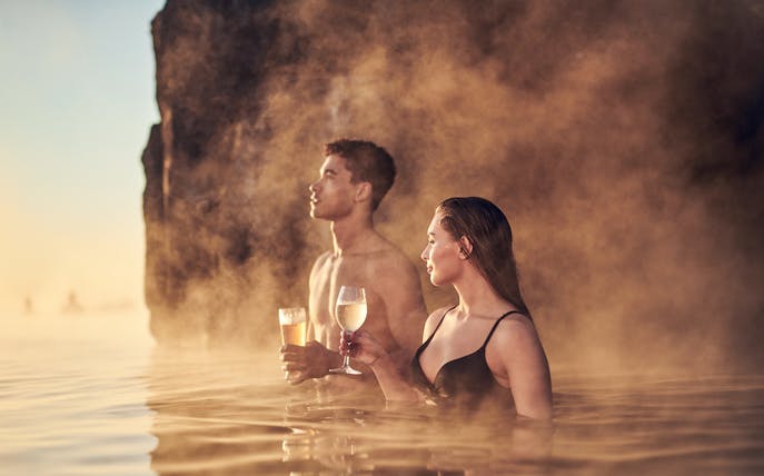 Couple enjoying drinks in the warm waters of Sky Lagoon Saman Pass.