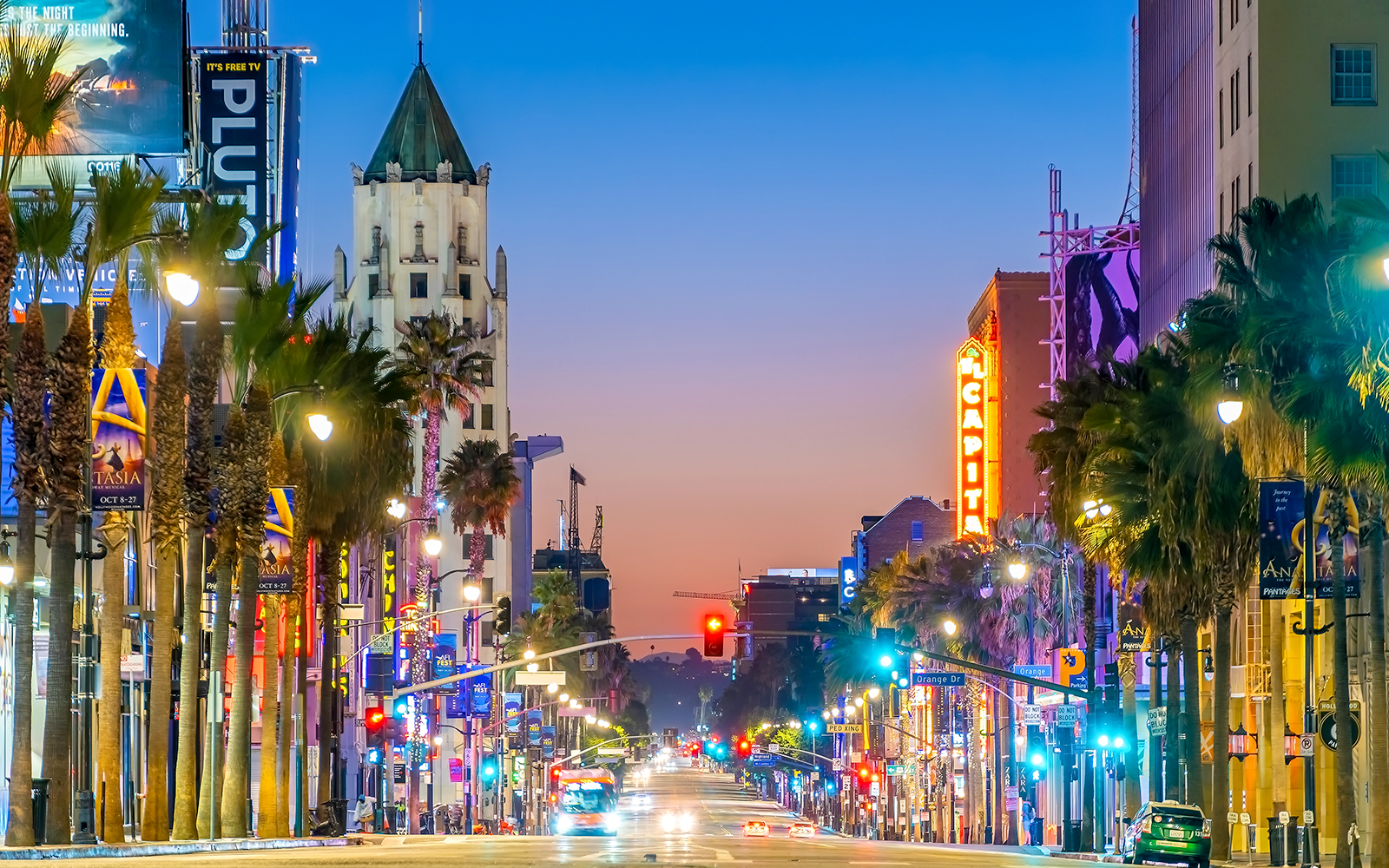 Hollywood Walk of Fame at dusk, Los Angeles, with neon lights and palm trees lining the street.