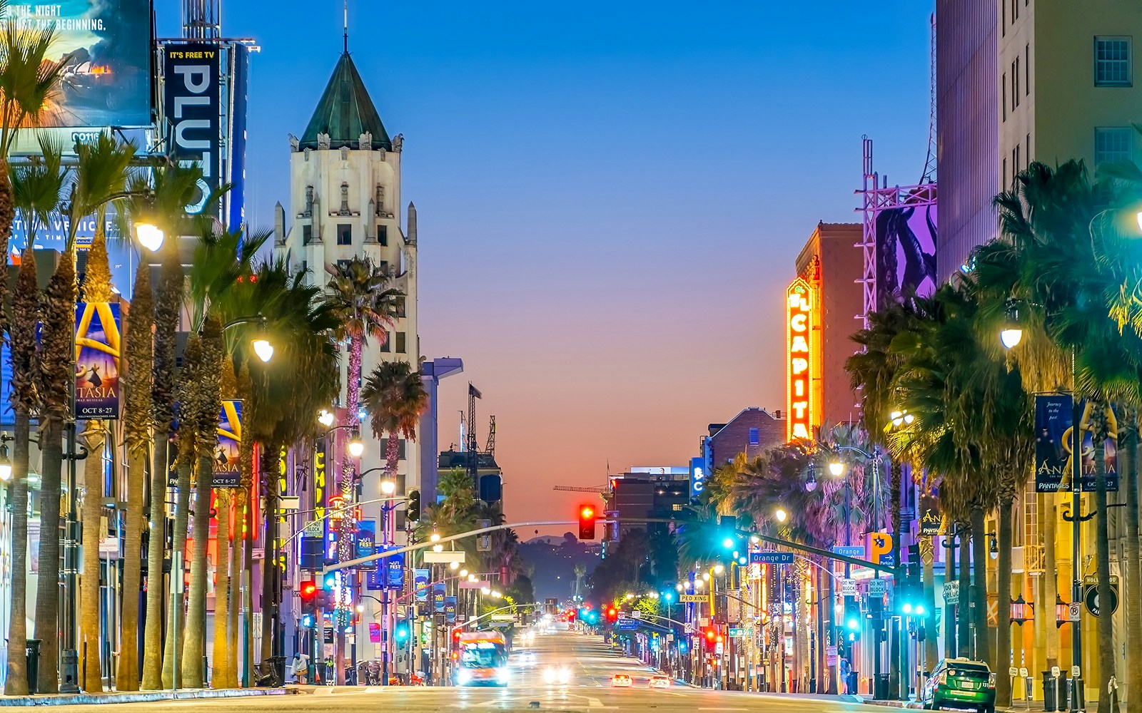 Sunset Boulevard at dusk, Los Angeles, with neon lights and palm trees lining the street.