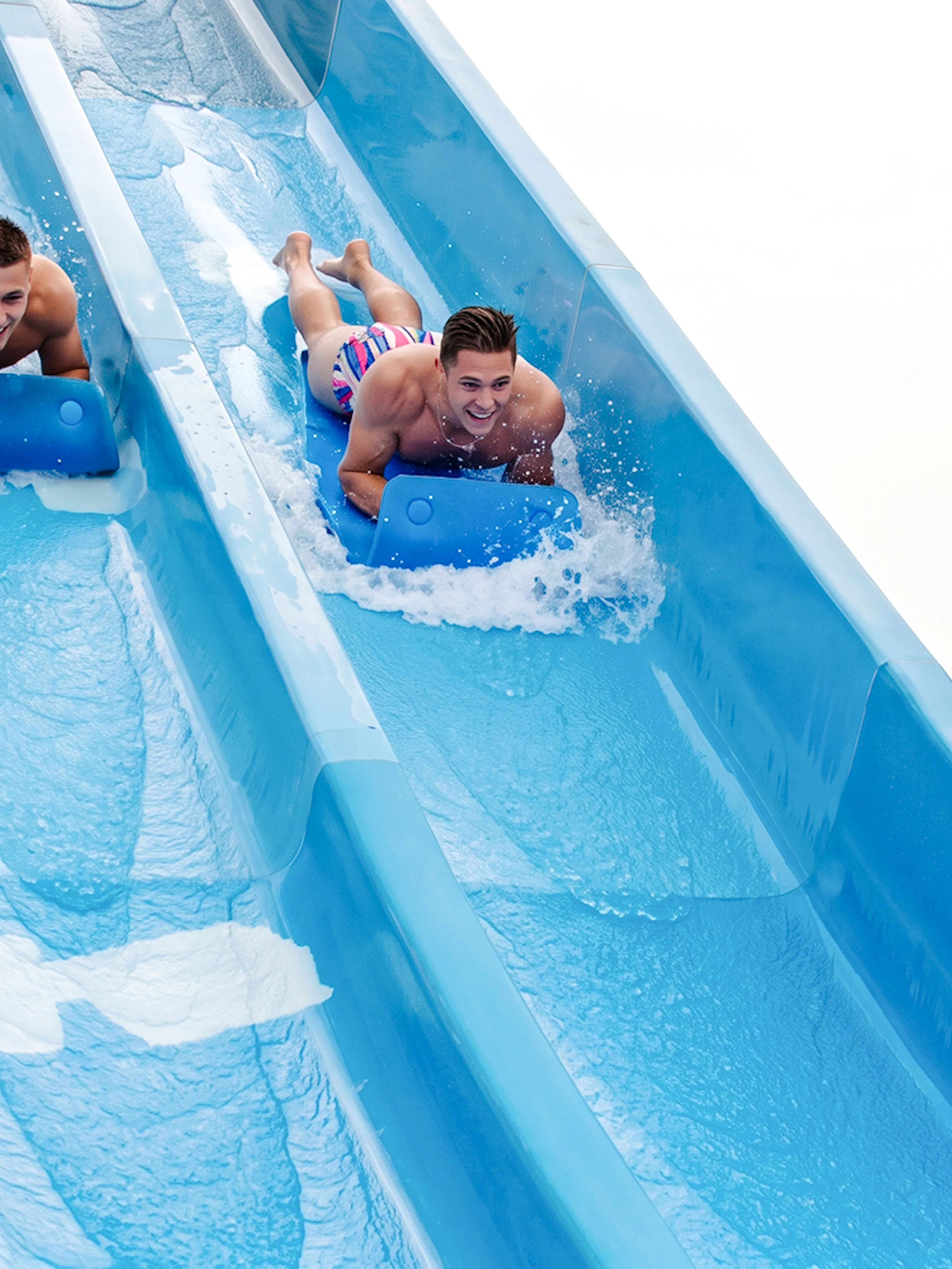 Two people sliding on water mats at Aquasplash Antibes.