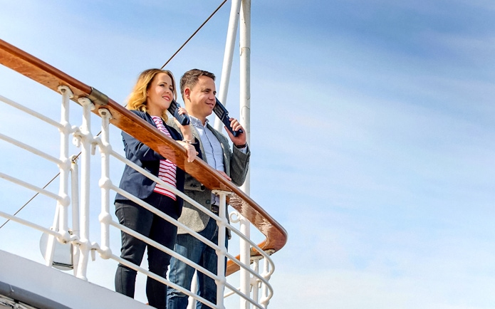 Couple enjoying a view from a ship deck with The Grande Ticket.