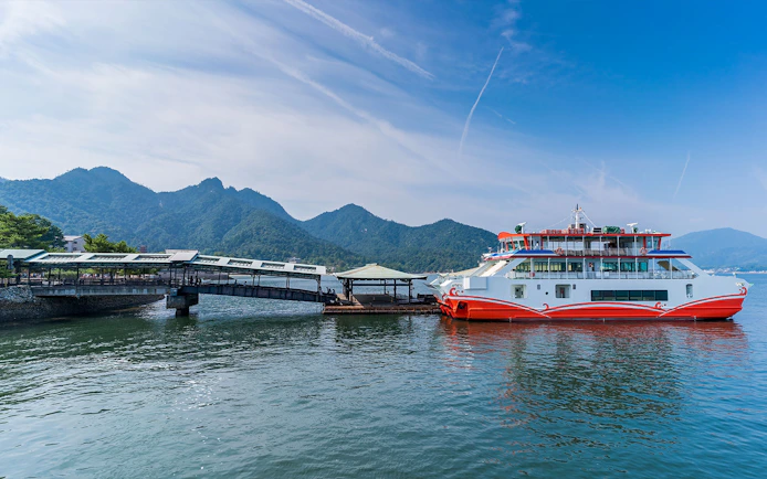 Ferry docked at Miyajima Island with mountains in the background, part of Hiroshima tour.
