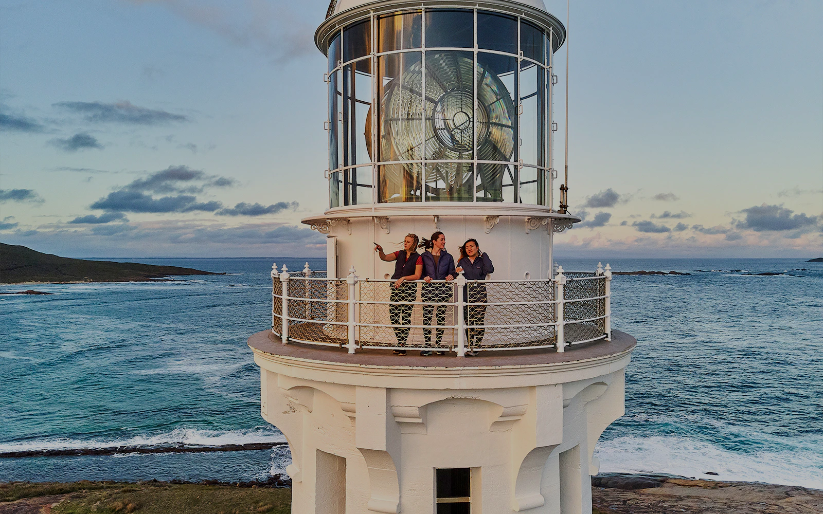 Visitors on Cape Leeuwin Lighthouse balcony overlooking ocean views.