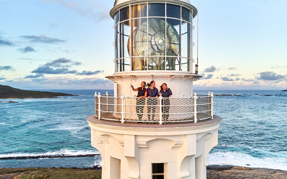 Visitors on Cape Leeuwin Lighthouse balcony overlooking ocean views.