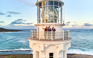 Visitors on Cape Leeuwin Lighthouse balcony overlooking ocean views.