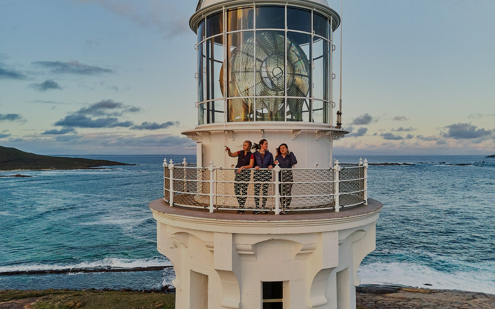 Visitors on Cape Leeuwin Lighthouse balcony overlooking ocean views.