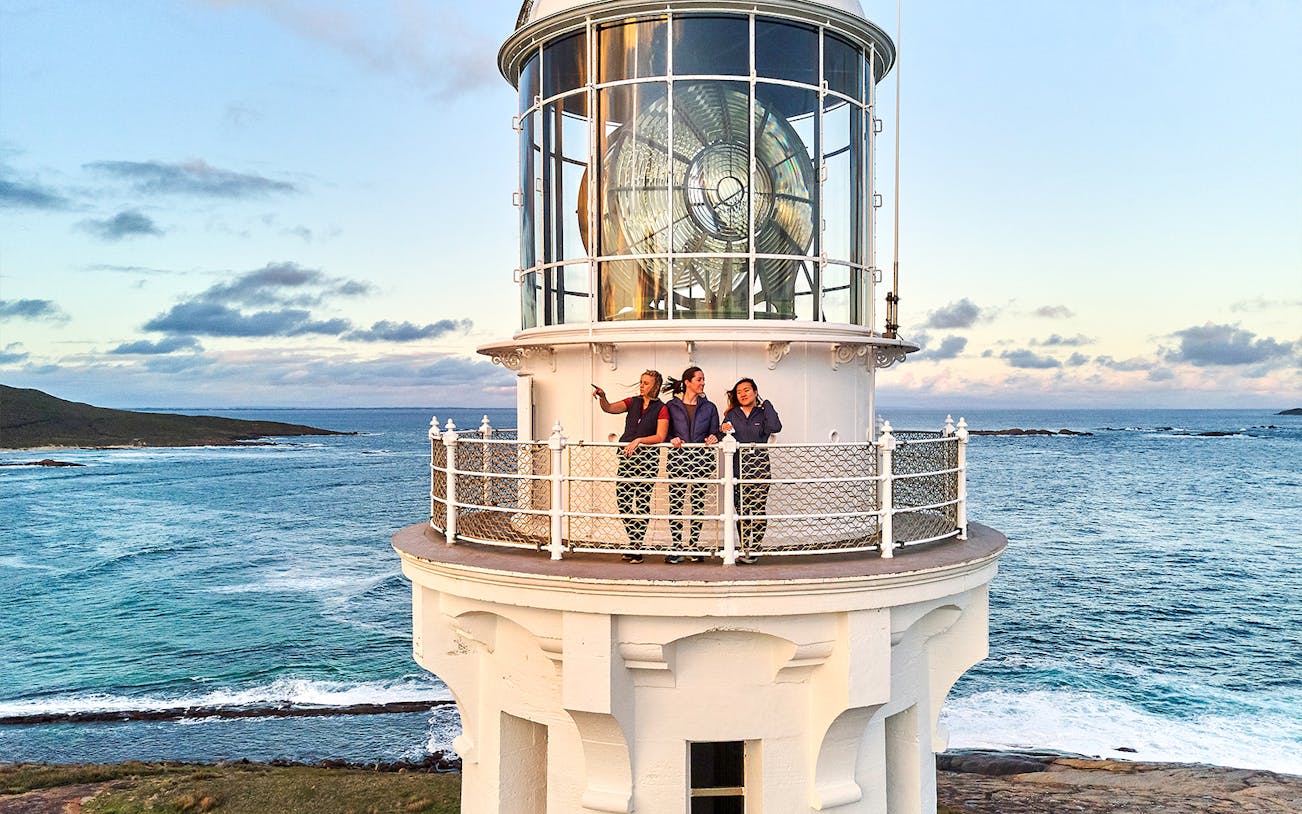 Visitors on Cape Leeuwin Lighthouse balcony overlooking ocean views.