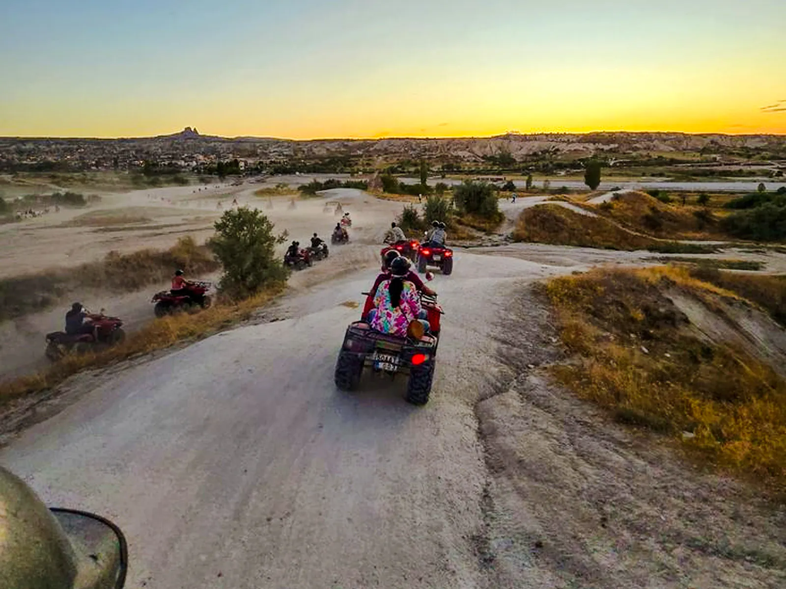 ATVs driving through Cappadocia's rocky landscape at sunset.