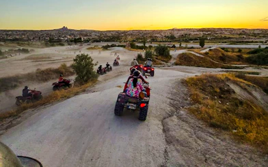 ATVs driving through Cappadocia's rocky landscape at sunset.