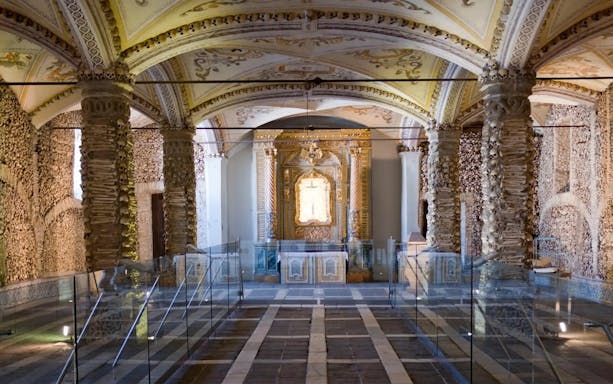 Capela dos Ossos interior with bone-decorated columns and ornate altar, Évora, Portugal.