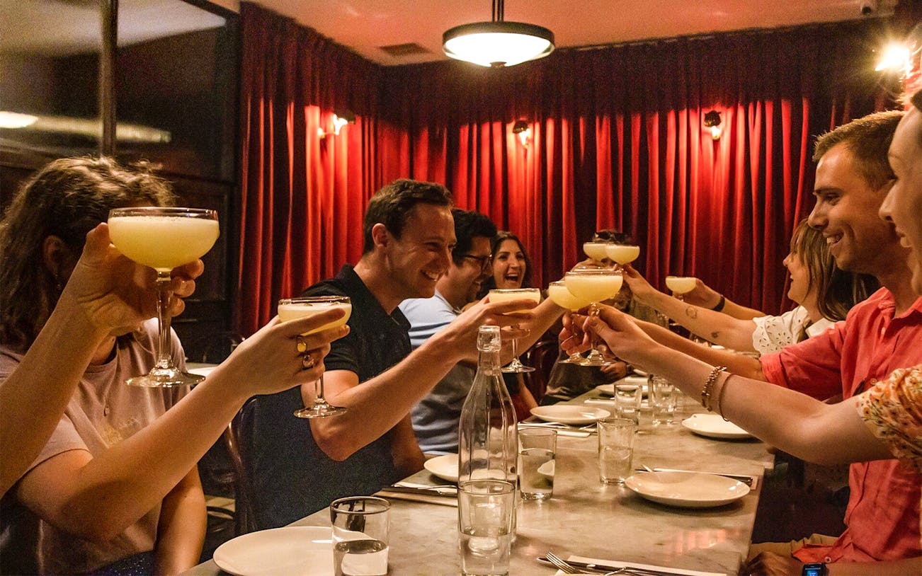 Group toasting with cocktails during Eating London: Twilight Soho Food & Drinks Tour.