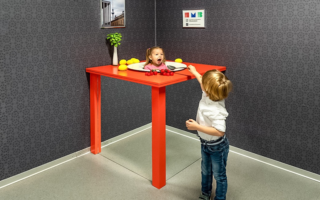Child interacting with optical illusion exhibit at Illuseum Berlin.