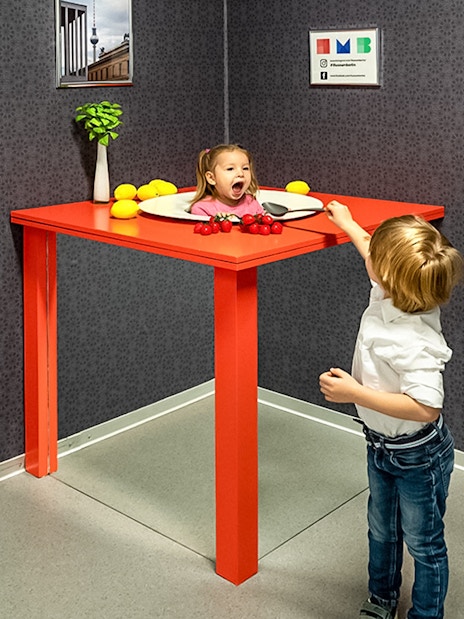 Child interacting with optical illusion exhibit at Illuseum Berlin.