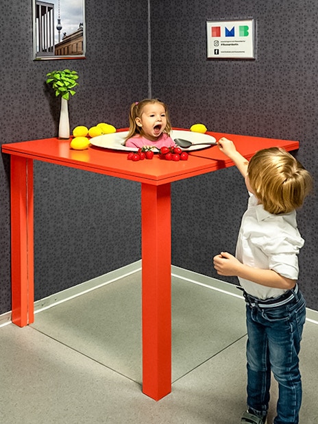 Child interacting with optical illusion exhibit at Illuseum Berlin.