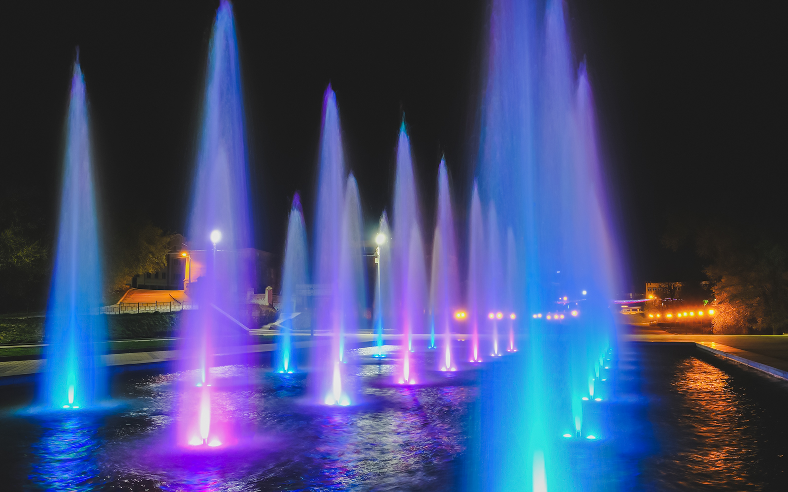 Colorful water fountain illuminated at night with vibrant lights.