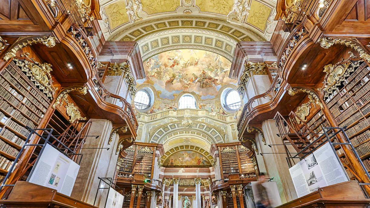 Austrian National Library State Hall with ornate baroque architecture and ceiling frescoes.