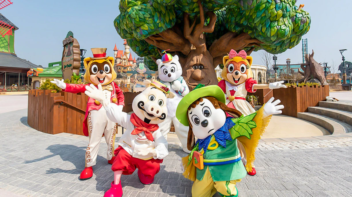 Characters in colorful costumes at Lotte World Adventure, Busan, with a whimsical tree backdrop.