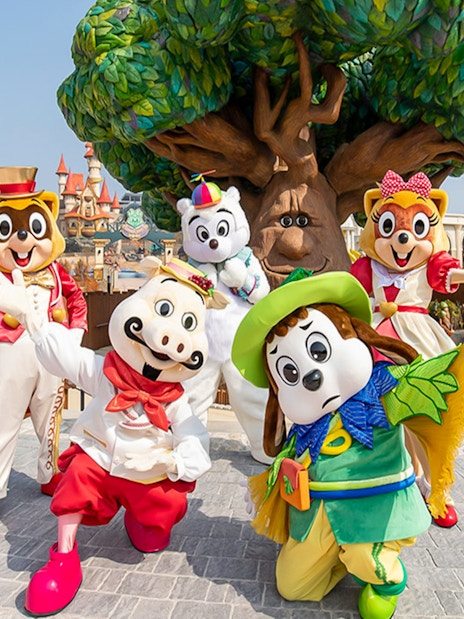 Characters in colorful costumes at Lotte World Adventure, Busan, with a whimsical tree backdrop.