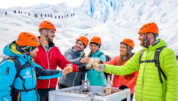 Tourists with guide toasting drinks atop Perito Moreno Glacier, Argentina.