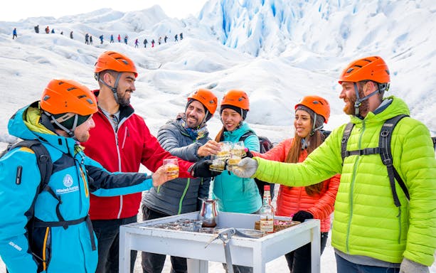 Tourists with guide toasting drinks atop Perito Moreno Glacier, Argentina.