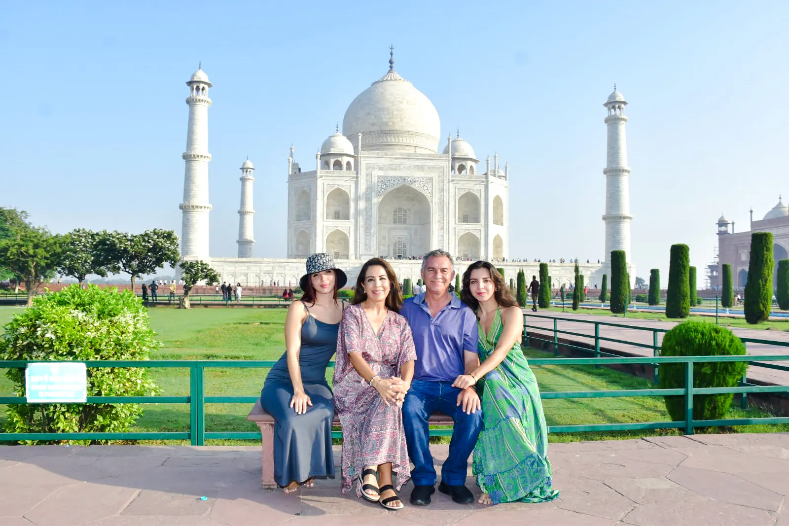 Family sitting in front of the Taj Mahal during sunrise tour in Agra.